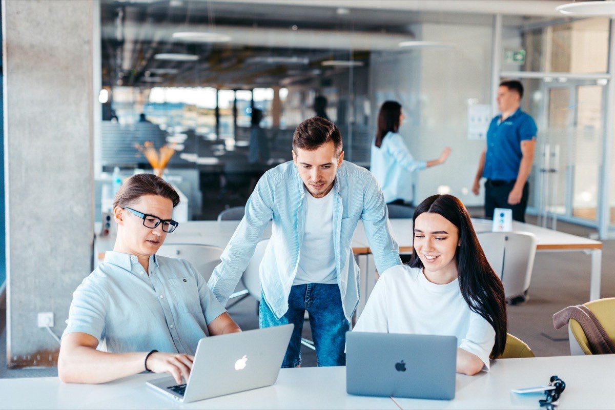 Equipo de trabajo colaborando frente a computadores portátiles en una oficina